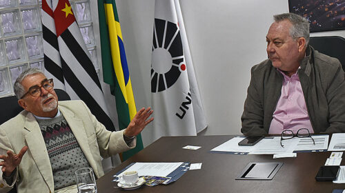 Reitor Paulo César Montagner sentado à cabeceira de mesa de reuniões, tendo à sua esquerda o secretário-geral da União das Universidades da América Latina e Caribe (Udualc), Roberto Escalante.