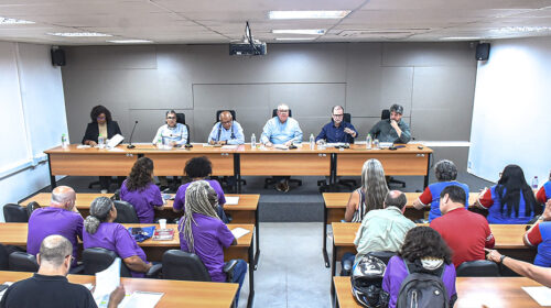 Reitor Paulo César Montagner e outros cinco membros da Administração Central da Universidade sentados lado a lado à mesa diretora de um auditório, de frente para plateia composta por integrantes do Sindicato dos Trabalhadores da Unicamp (STU).