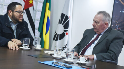 Reitor Paulo César Montagner sentado à cabeceira de mesa de reuniões, tendo à sua esquerda o prefeito de Paulínia, Danilo Barros.