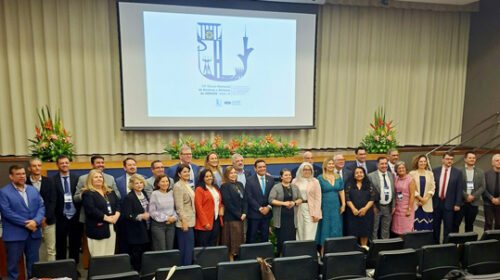 Participantes do 74º Fórum Nacional de Reitoras e Reitores da Associação Brasileira dos Reitores das Universidades Estaduais e Municipais (Abruem) posam para foto de pé, lado a lado, entre a mesa diretiva e os assentos, todos vazios, de um auditório.