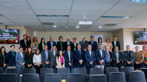 Representantes da Unicamp e de delegação de Macau, totalizando quase 30 pessoas, posam para foto em um auditório, em pé, alinhados em duas fileiras posicionadas em alturas diferentes.