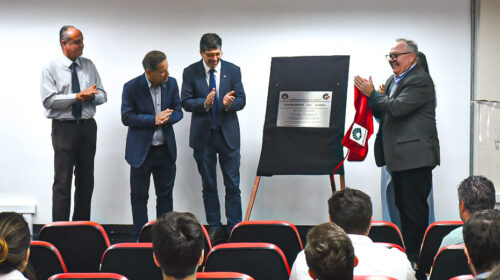 O reitor da Unicamp, Paulo Cesar Montagner (à direita), e outros quatro representantes da Universidade, dos quais três homens e uma mulher, estão no palco de um auditório posicionados ao redor de um cavalete, no qual está apoiada a placa comemorativa dos 35 anos do Gastrocentro.